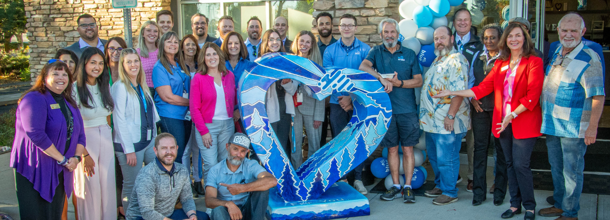 Local artist with Blue Federal Credit Union staff at the Loveland heart presentation.